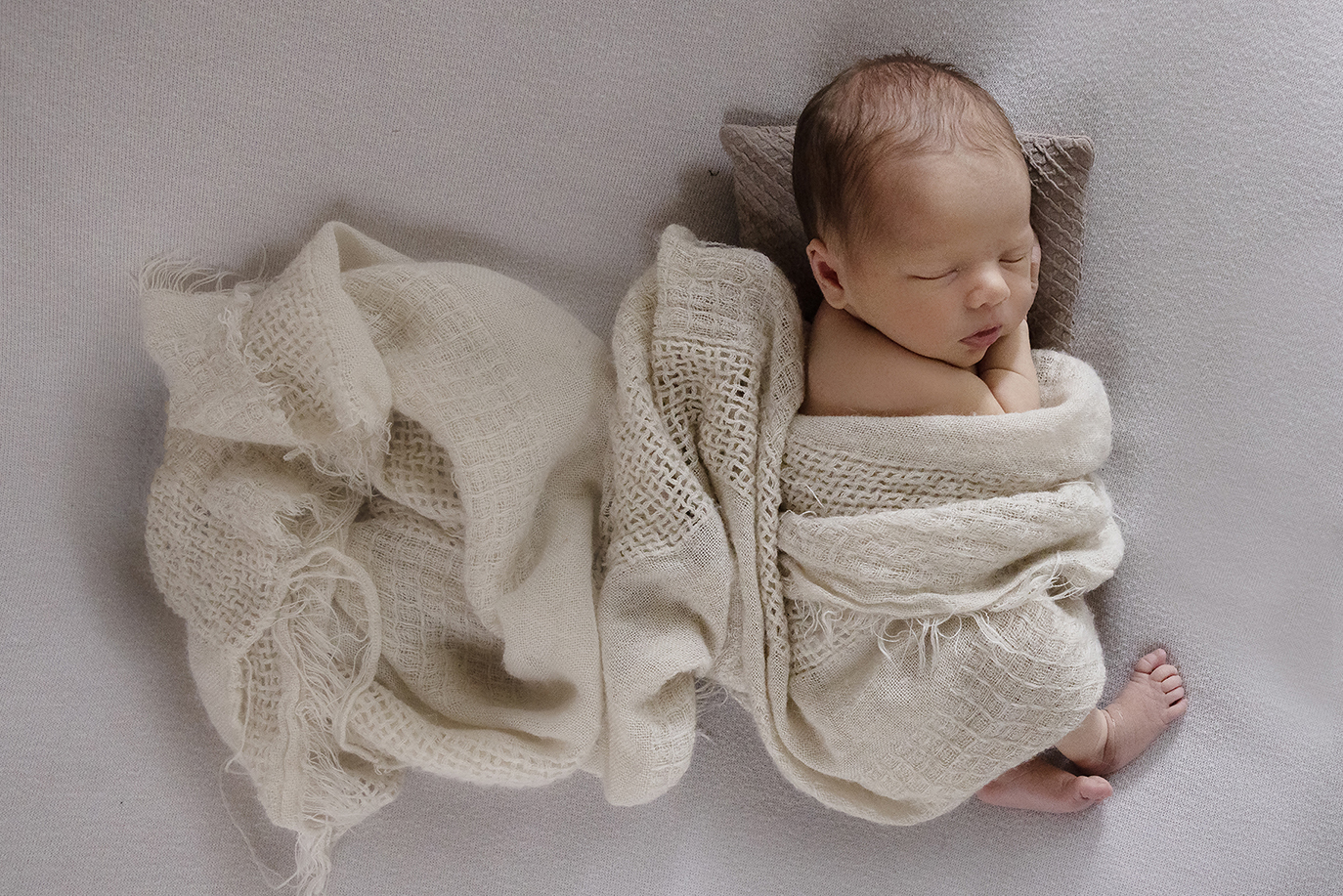Sussex photographer for newborn babies image of baby swaddled in oatmeal wrap