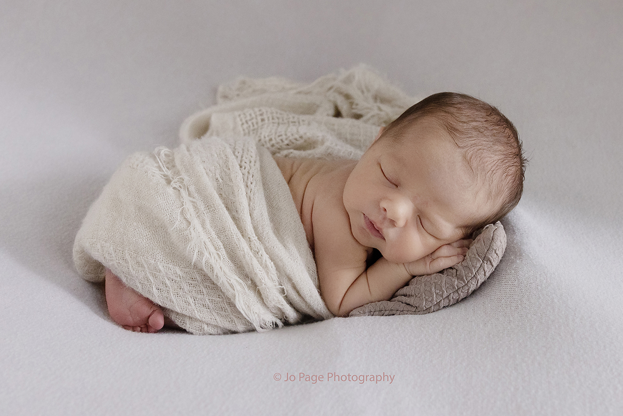 baby swaddled on bean bag in Sussex newborn photographer image
